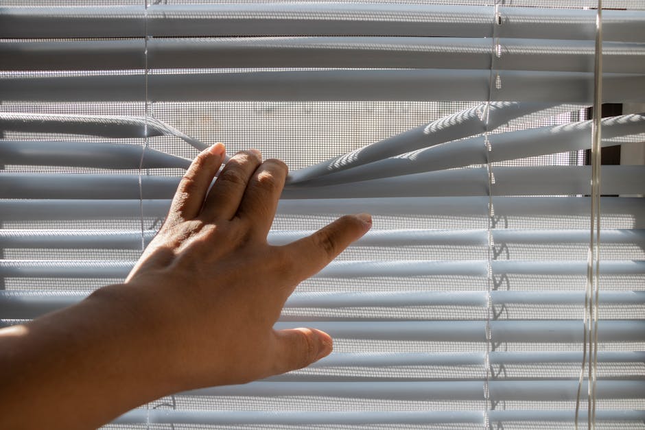 Woman adjusting elegant window blinds in a sunlit room